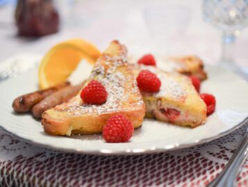 Stuffed french toast is topped with fresh raspberries and powdered sugar.